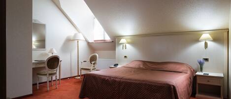 Ein Schlafzimmer mit einem großen Bett, einem Schreibtisch, einem Sessel und einem Nachttisch.