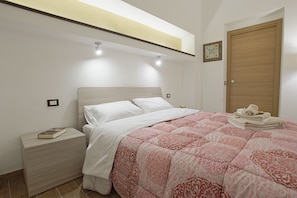 A bedroom with a bed, nightstand, and a door.