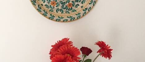 A decorative plate with a floral pattern and a vase with red flowers.