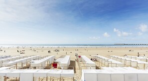 Ein Strand mit Reihen weißer Zelte, feinem Sand und blauem Himmel.