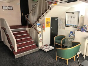 A staircase with red steps, a reception desk, two green chairs, and a map on the wall. - Hôtel du Commerce (Les Sables-d'Olonne)