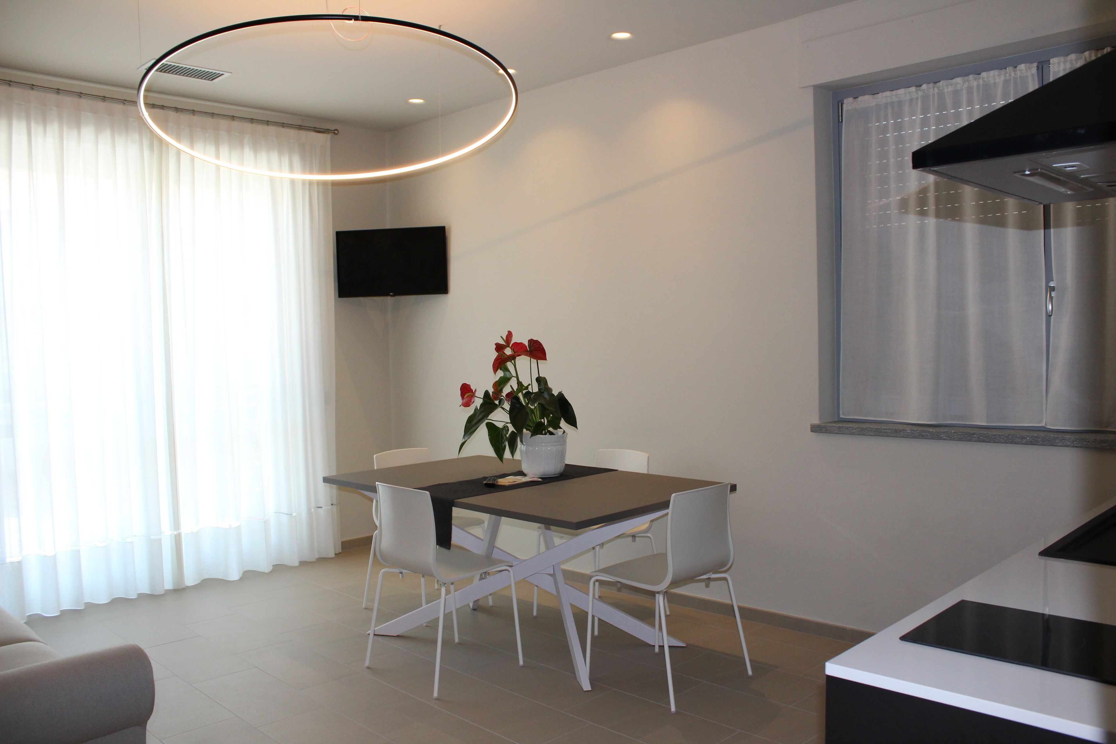 A modern kitchen with a built-in stove, a dining area with a table and chairs, and a TV mounted on the wall.