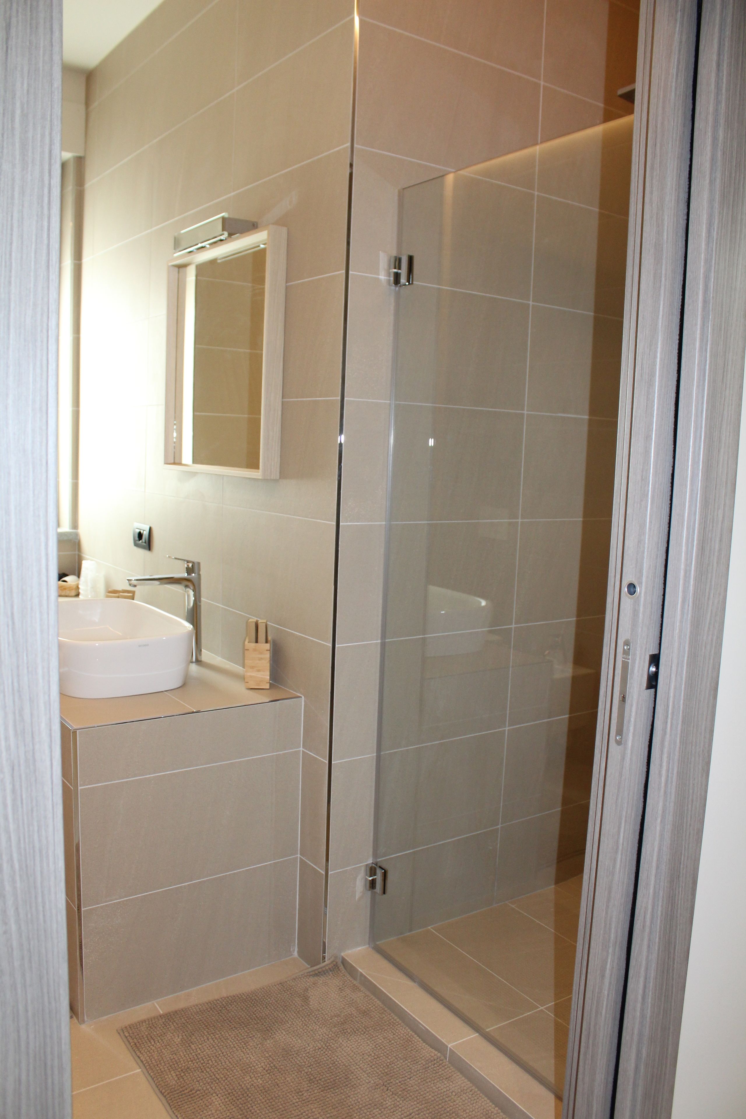 A modern bathroom with a glass-enclosed shower, a white sink, and a mirror above the sink.