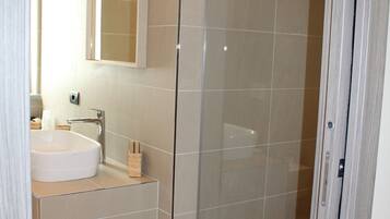 A modern bathroom with a glass-enclosed shower, a white sink, and a mirror above the sink.
