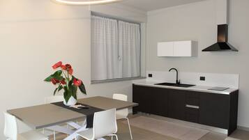Una cocina moderna con una decoración en blanco y negro, un comedor con mesa y sillas, y un ventanal con cortinas.