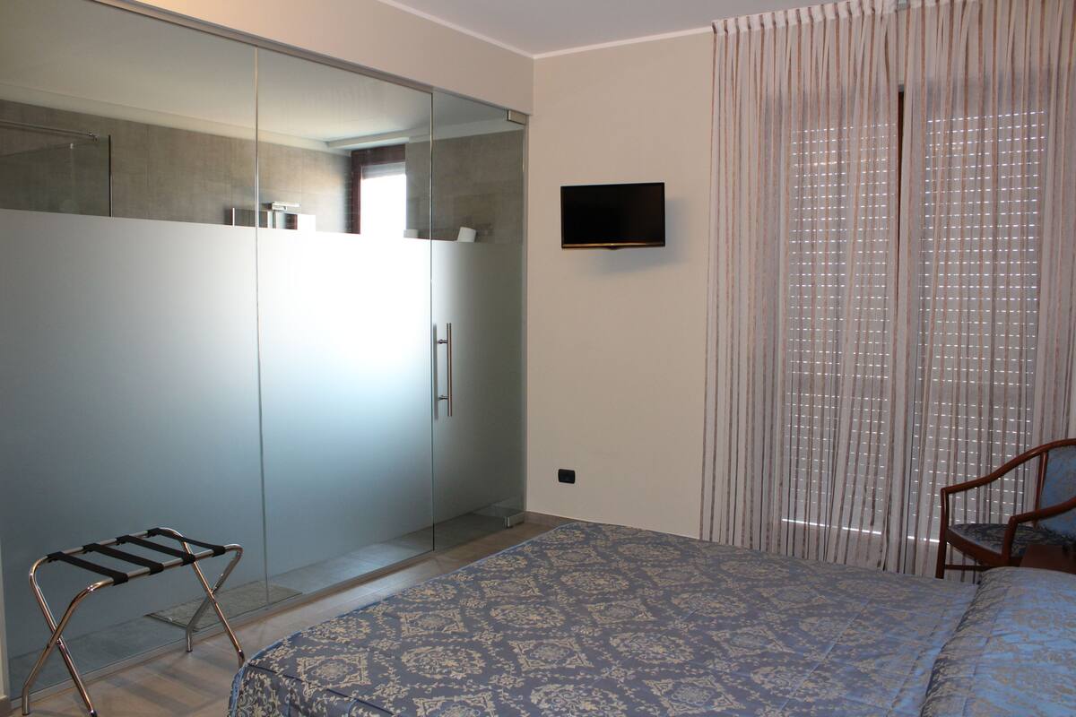 Ein Schlafzimmer mit Bett, Kleiderschrank, Fernseher und Stuhl.
