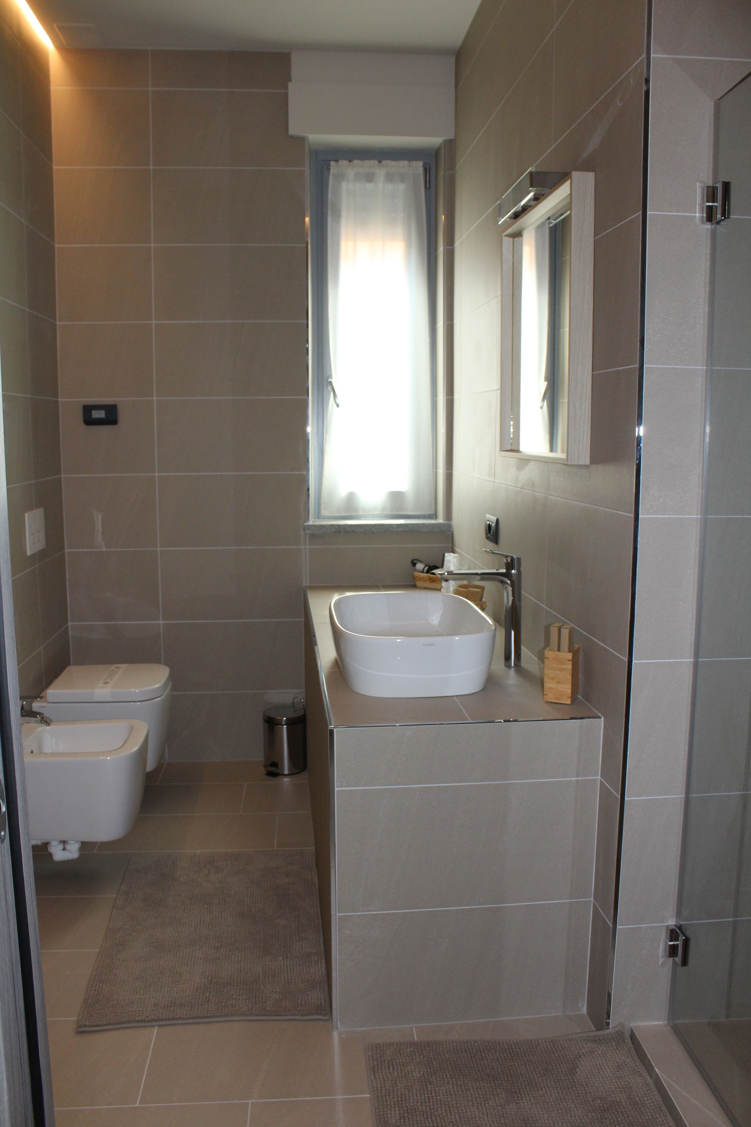 A modern bathroom with a toilet, bidet, sink, and a mirror above the sink.