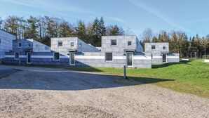 A modern building with a concrete exterior, multiple windows, and a gravel driveway. - Beautiful studio in Løgumkloster (Løgumkloster)