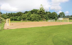 Un terrain de football avec deux buts, entouré d’une zone herbeuse et d’arbres.