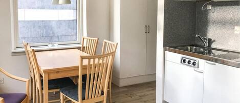 A compact kitchen with white cabinets, a black countertop, and a window with a view.