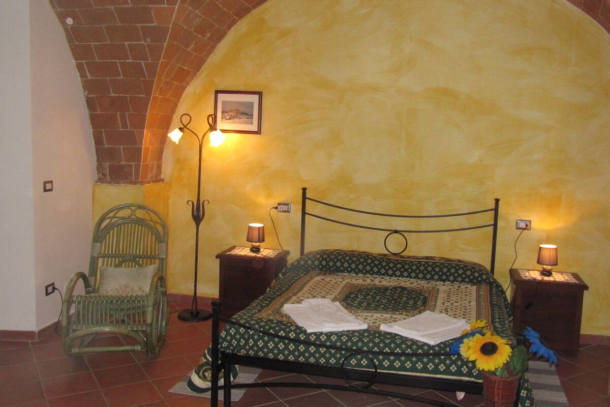 Ein Zimmer mit einem Bett, zwei Nachttischlampen, einem Sessel und einem Bild an der Wand.