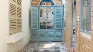 A hotel entrance with a blue door, a sign above it, and a tiled walkway leading to the door. - KHA Hostel & Cafe (Ho Chi Minh City)