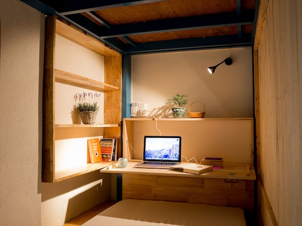 A cozy workspace with a laptop, books, and decorative items on shelves.