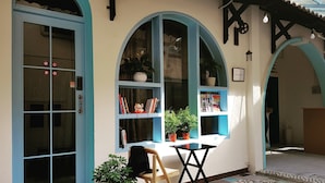 A room with a blue-framed window, a small table, a chair, and a potted plant. - KHA Hostel & Cafe (Ho Chi Minh City)