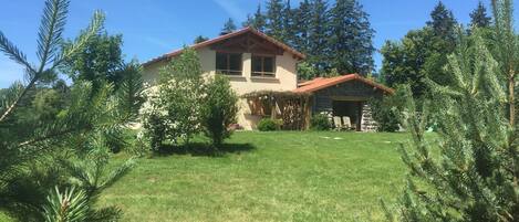 A house with a stone exterior, a red roof, and a well-maintained lawn.