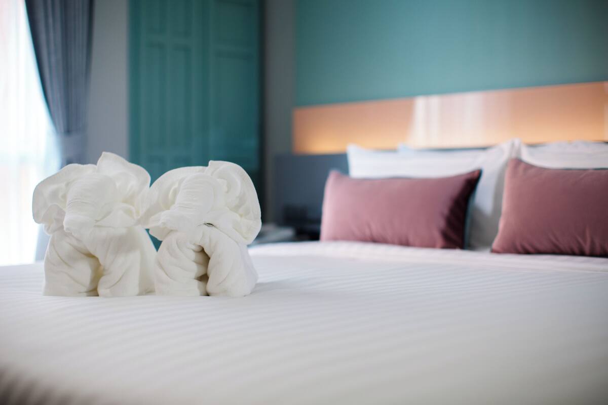 A neatly made bed with white linens and two plush white pillows.