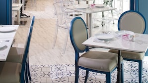 Un comedor moderno con sillas y mesas claras, una isla central con televisor, y un amplio ventanal que proporciona luz natural.