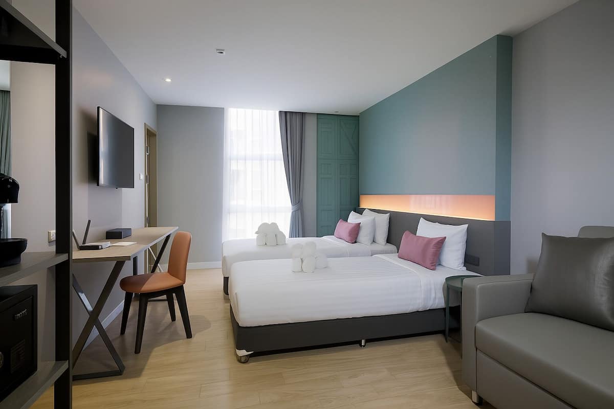 A modern hotel room with a bed, a desk, and a chair.