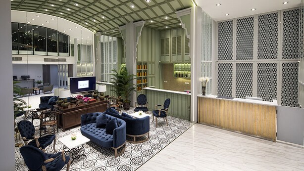 Un hall espacioso con techo curvo, una zona de estar con sofás y sillones, un televisor y un área de bar con un revestimiento de pared decorativo.