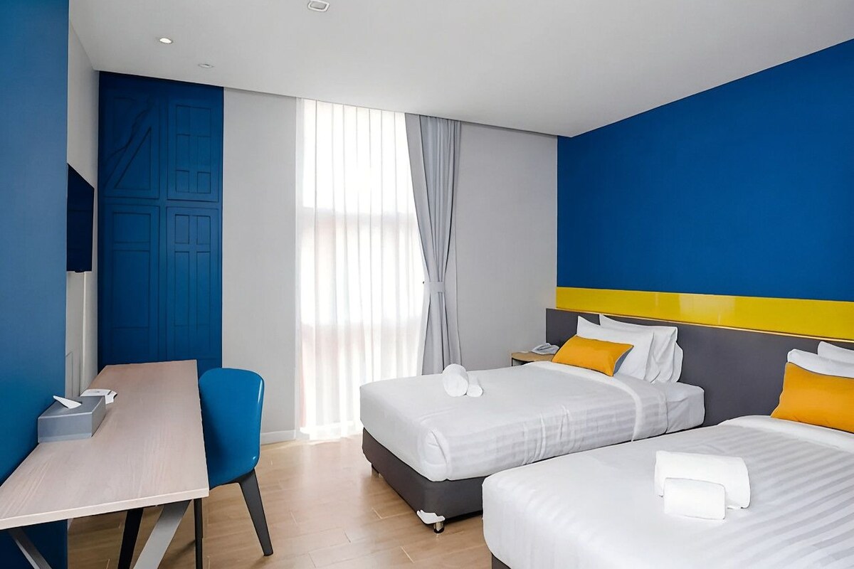 A hotel room with two beds, a desk, and a chair.
