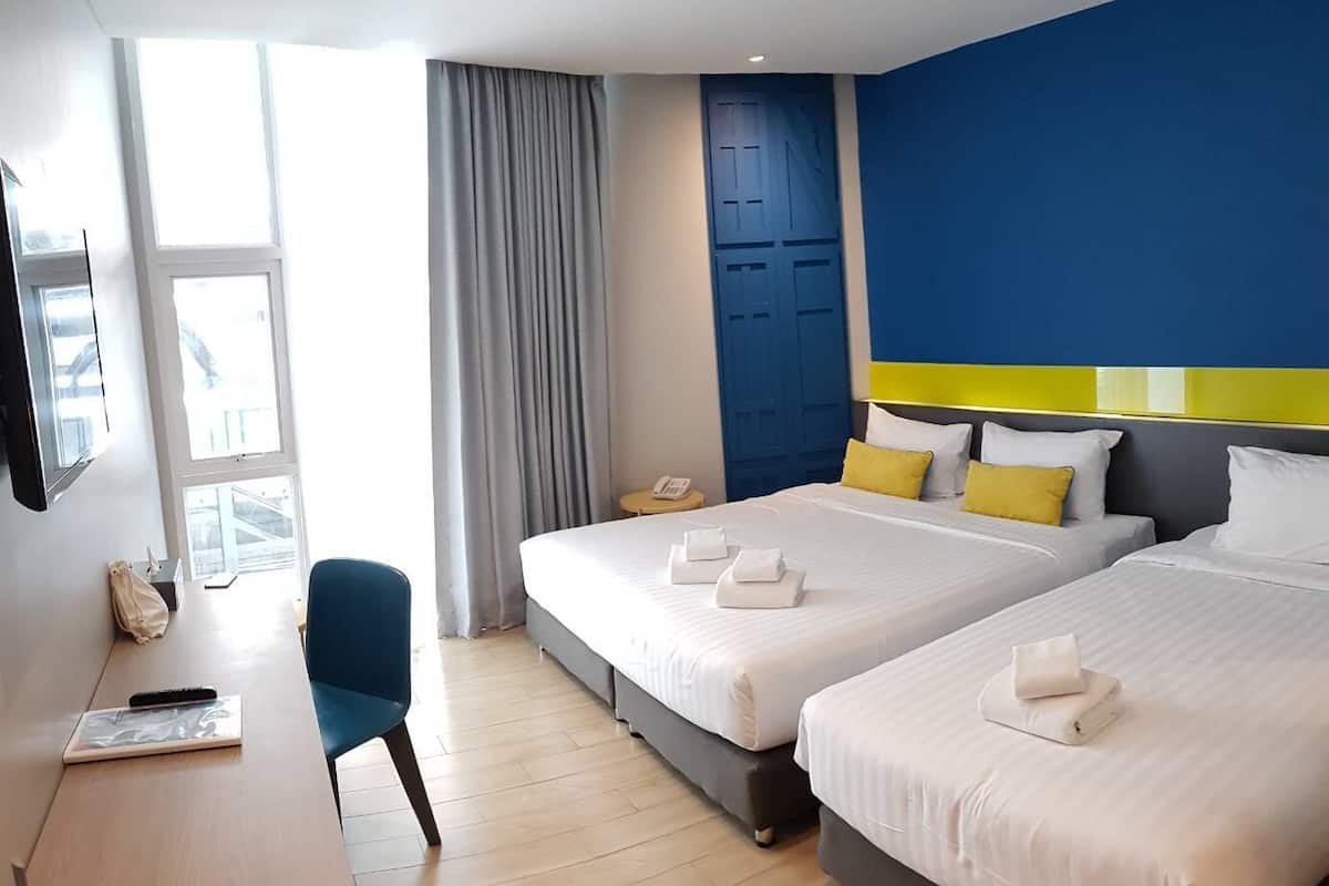 A hotel room with two beds, a desk, a chair, a phone, and a window with curtains.