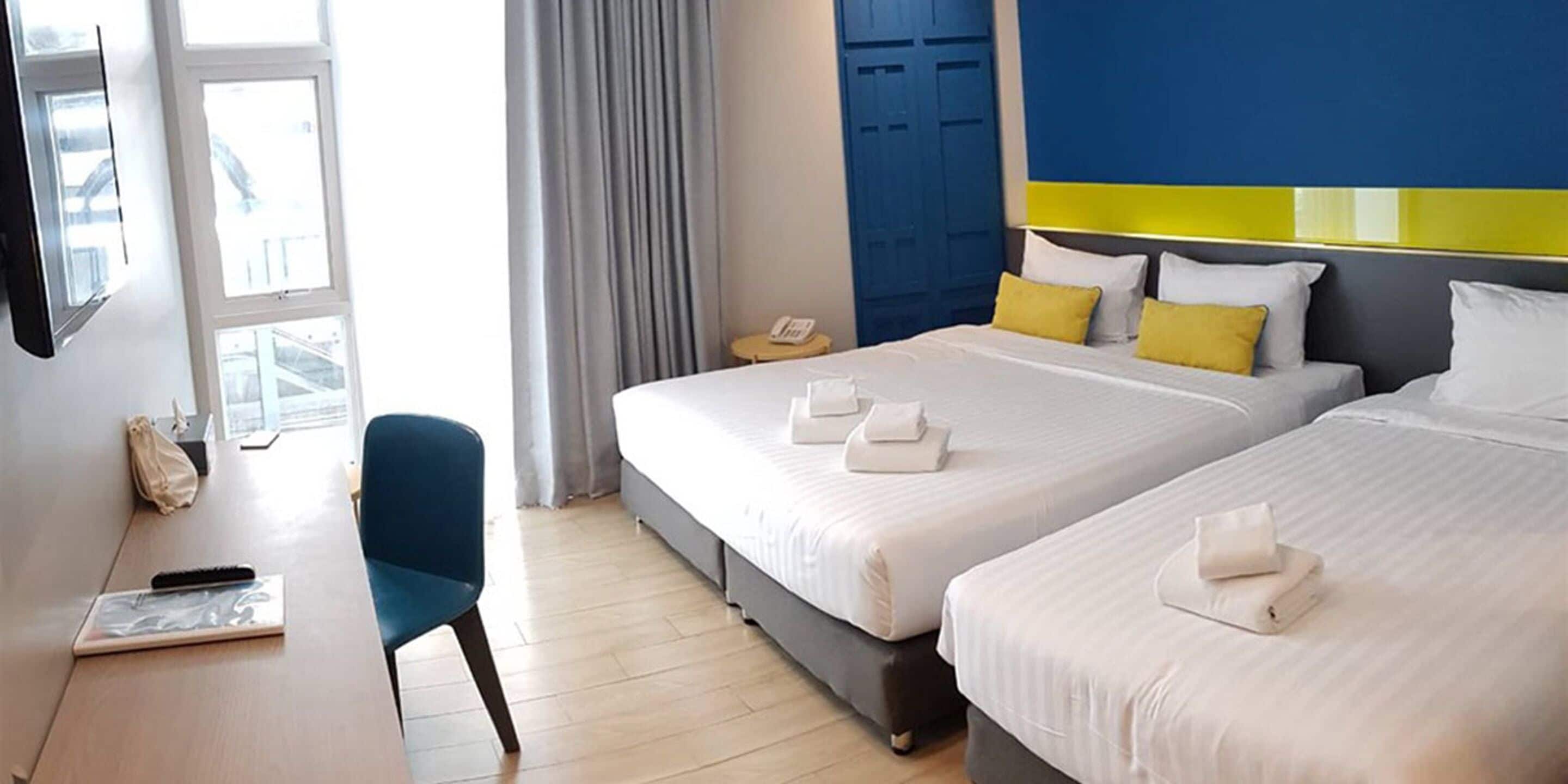 A hotel room with two beds, a desk, and a chair.