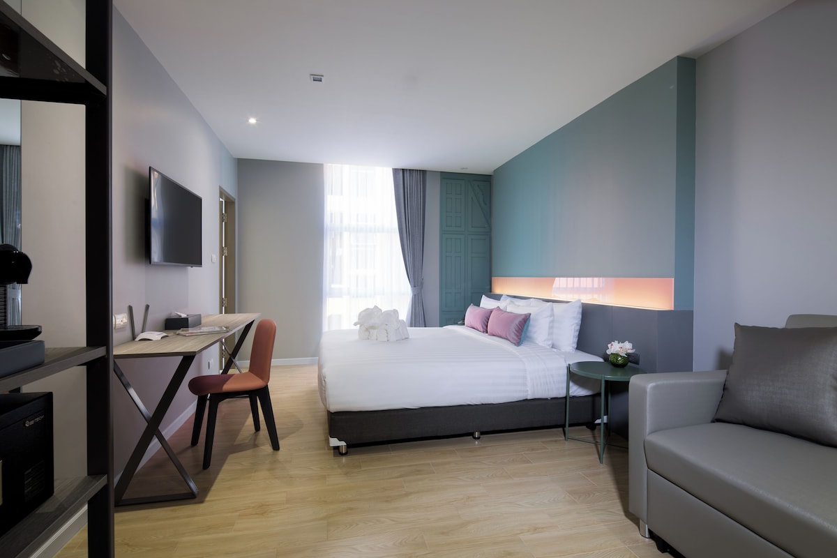 A modern hotel room with a bed, desk, and seating area.