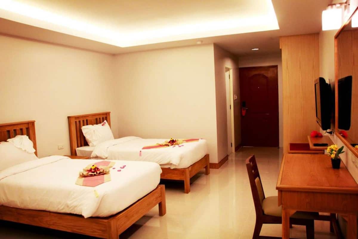 A hotel room with two beds, a wooden desk, and a mirror.