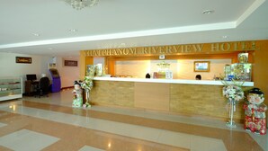 A reception desk at the Hat Phanom Riverside Hotel with a modern design, a reception area, and a decorative statue. - Thatphanom River View Hotel (That Phanom)