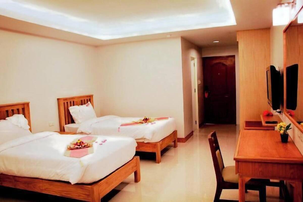 A hotel room with two beds, a wooden desk, a chair, and a television.