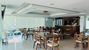 A spacious indoor dining area with multiple wooden tables and chairs, a reception desk, and a ceiling with recessed lighting. - Thatphanom River View Hotel (That Phanom)