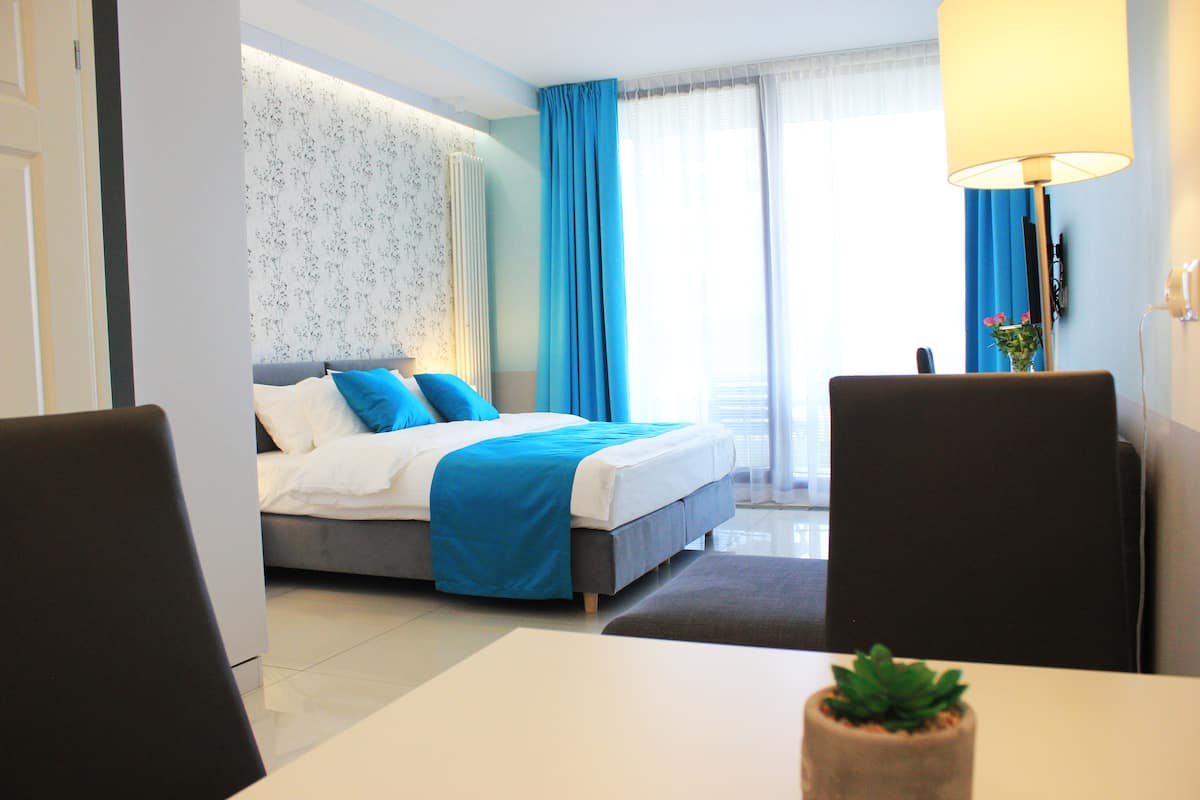 A modern hotel room with a bed, a desk, and a chair.