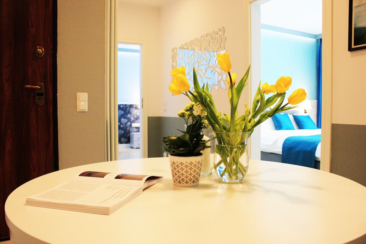 A round table with a book, a potted plant, and a vase with flowers.