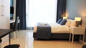 Ein Hotelzimmer mit Bett, Nachttischen, einem Schreibtisch und einem Sessel.