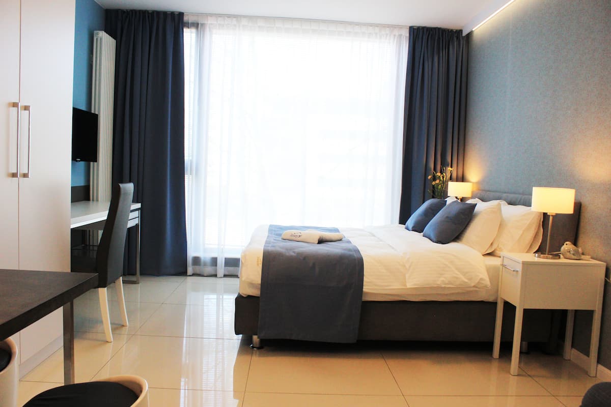 A hotel room with a bed, bedside tables, a desk, and a chair.