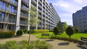 Ein modernes Mehrfamilienhaus mit Balkonen, einem gepflegten Rasen und einer Bank.