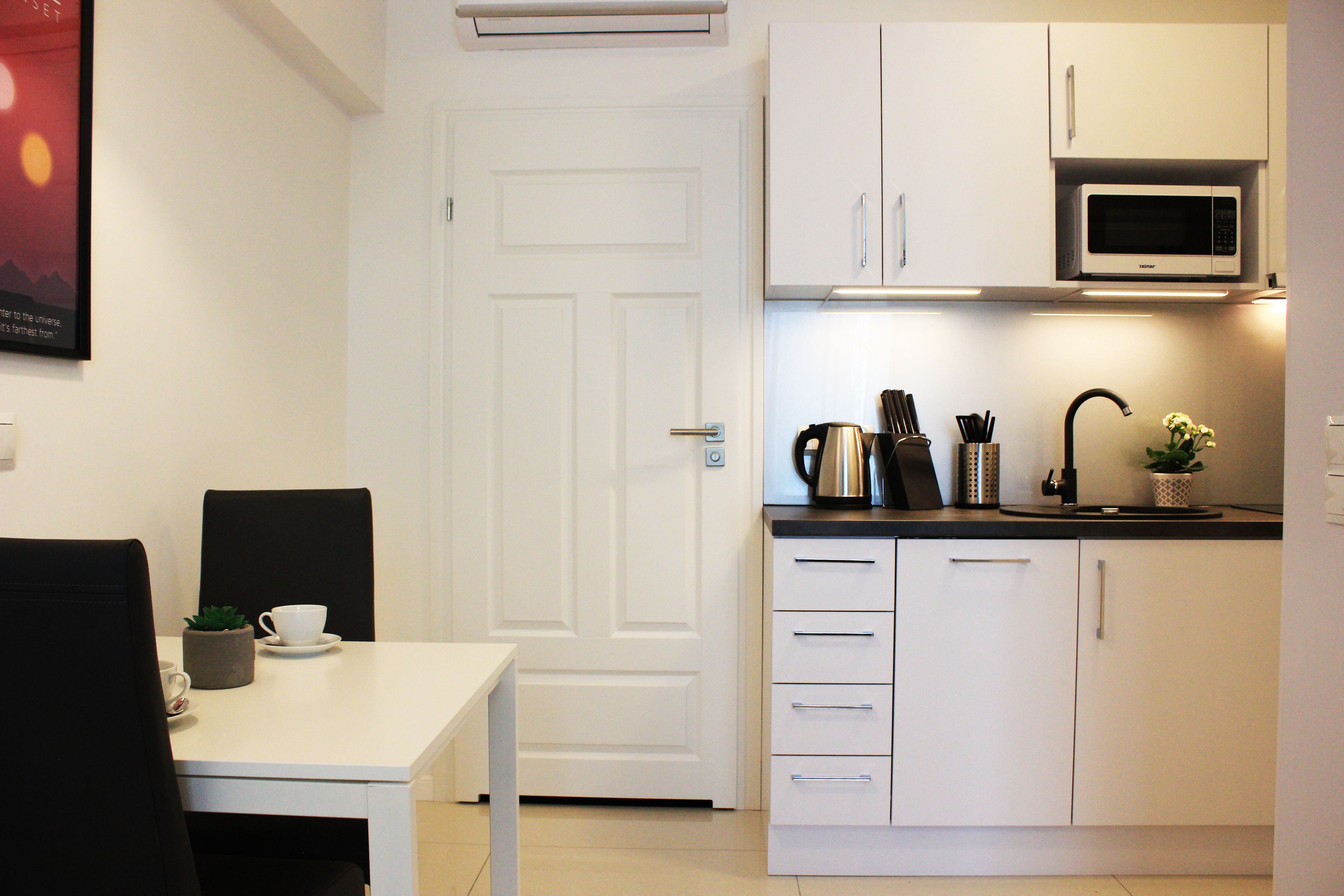 A compact kitchen with white cabinets, a microwave, and a coffee maker.