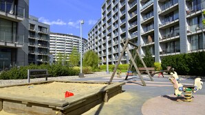 Ein Spielplatz mit Wippe, Sandkasten und Schaukeln.