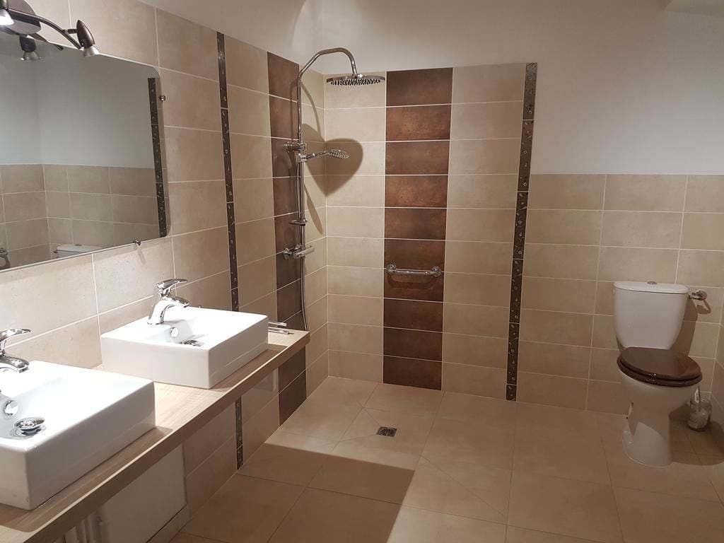 Un baño con dos lavamanos, ducha e inodoro.
