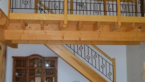 Una escalera de madera con barandilla, un armario de madera y una pequeña mesa.