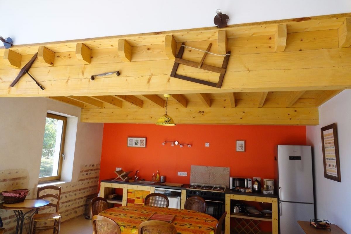 Eine kompakte Küche mit Holzbalken, ein Essbereich mit Tisch und Stühlen sowie ein Fenster, das für natürliches Licht sorgt.