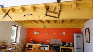 Eine kompakte Küche mit Holzbalken, ein Essbereich mit Tisch und Stühlen sowie ein Fenster, das für natürliches Licht sorgt.