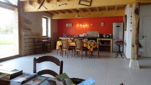 Un comedor con vigas de madera, una pared roja y una cocina al fondo.