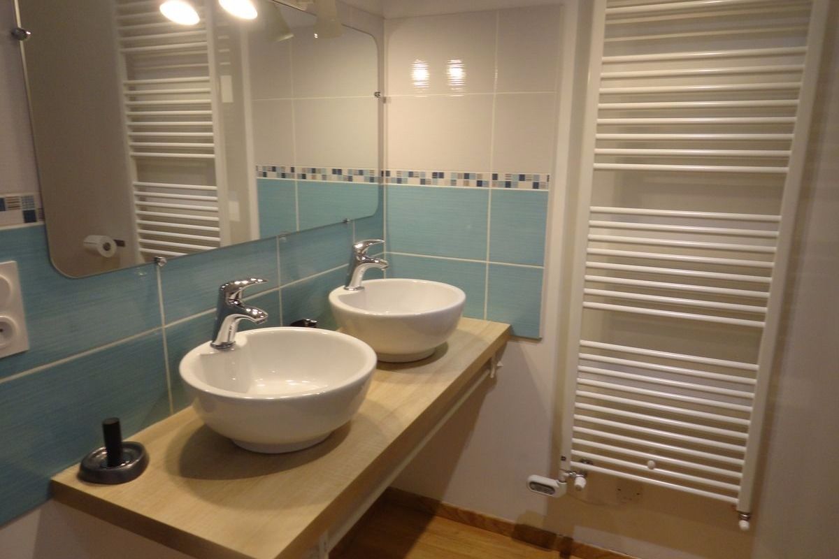 Un baño con dos lavamanos, un espejo y un perchero para toallas.