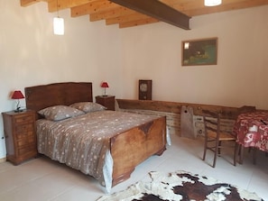 A bedroom with a wooden bed, a bench, a table, and a cowhide rug. - Ferme Passion (Saint-Trivier-sur-Moignans)