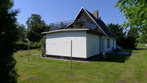 Une petite maison à un seul étage, avec une façade blanche et un toit en pente.