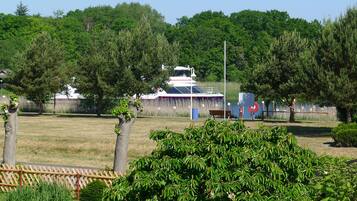 A boat docked near a grassy area with trees and a fence.