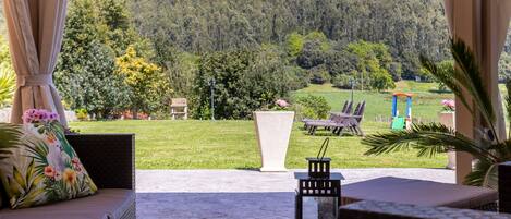 A covered outdoor seating area with a view of a forested hillside.