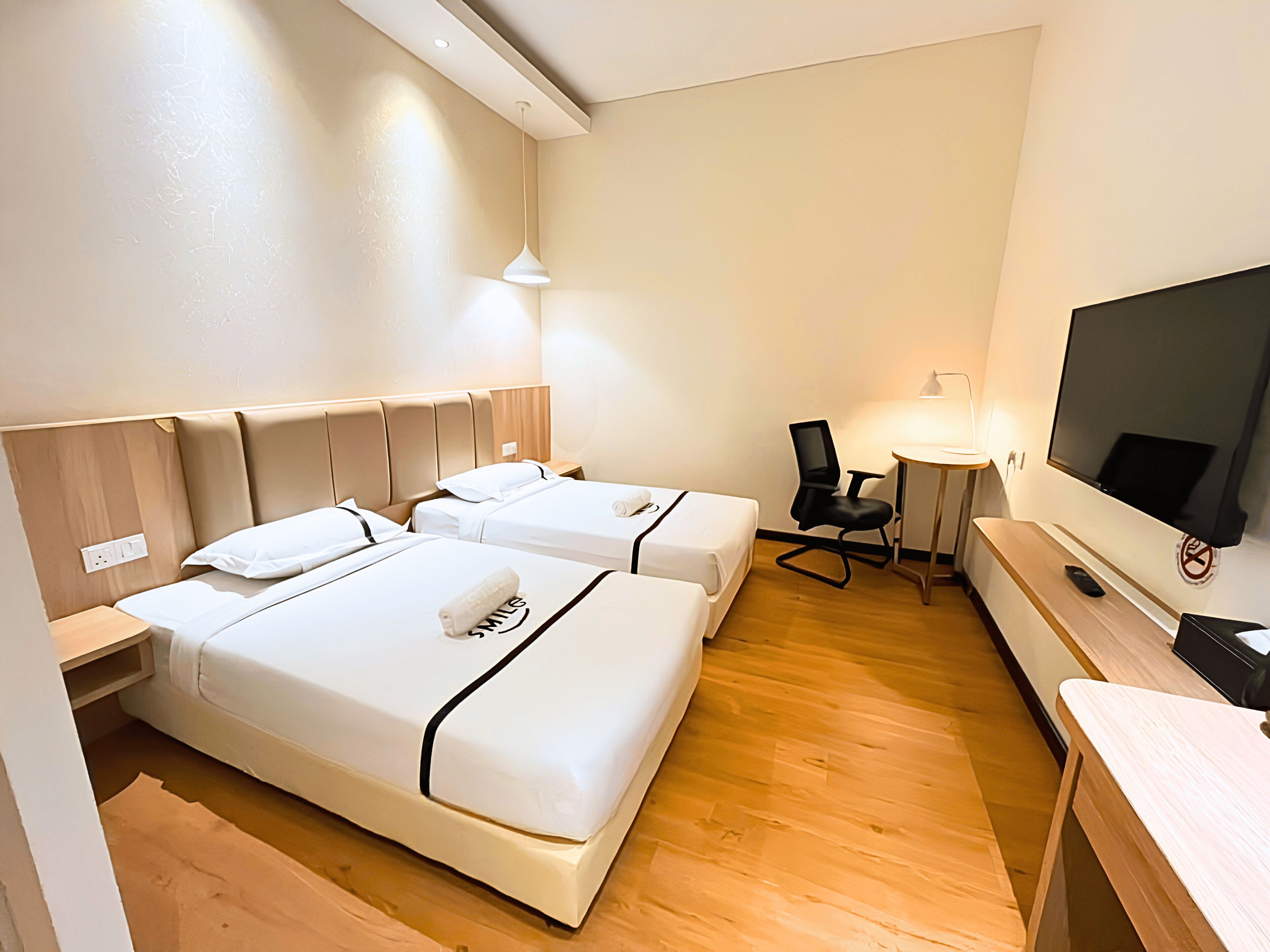 Une chambre d’hôtel avec deux lits, un bureau, une chaise, une télévision et une lampe.