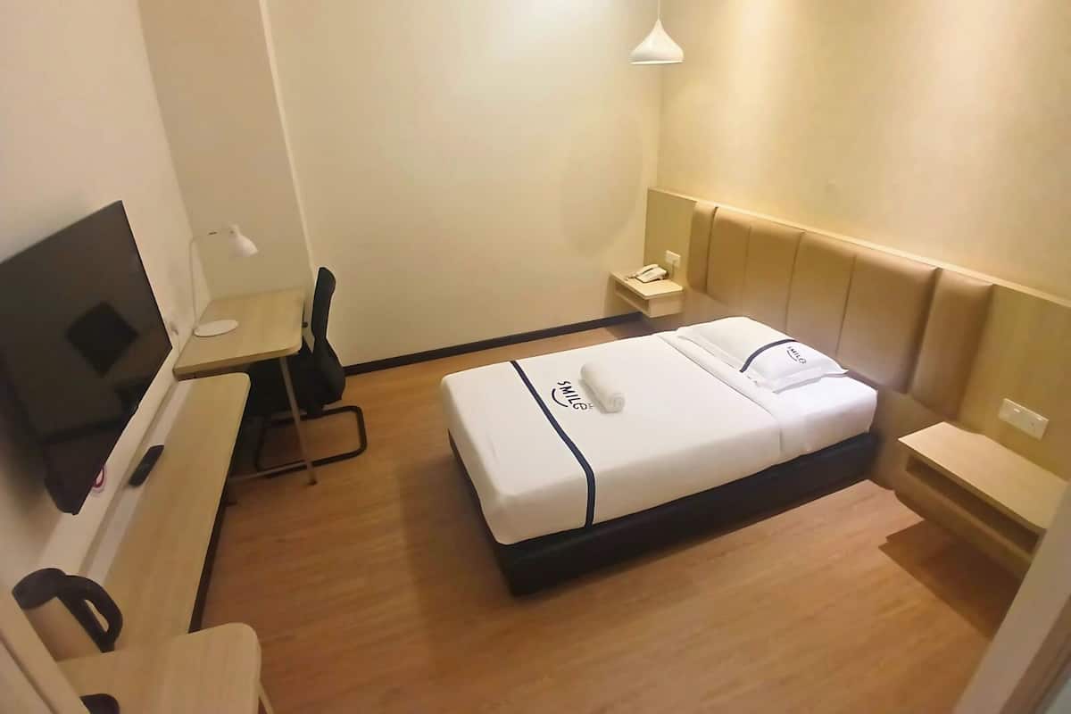 Ein Hotelzimmer mit einem Bett, einem Schreibtisch, einem Stuhl, einem Fernseher und einem Nachttisch.
